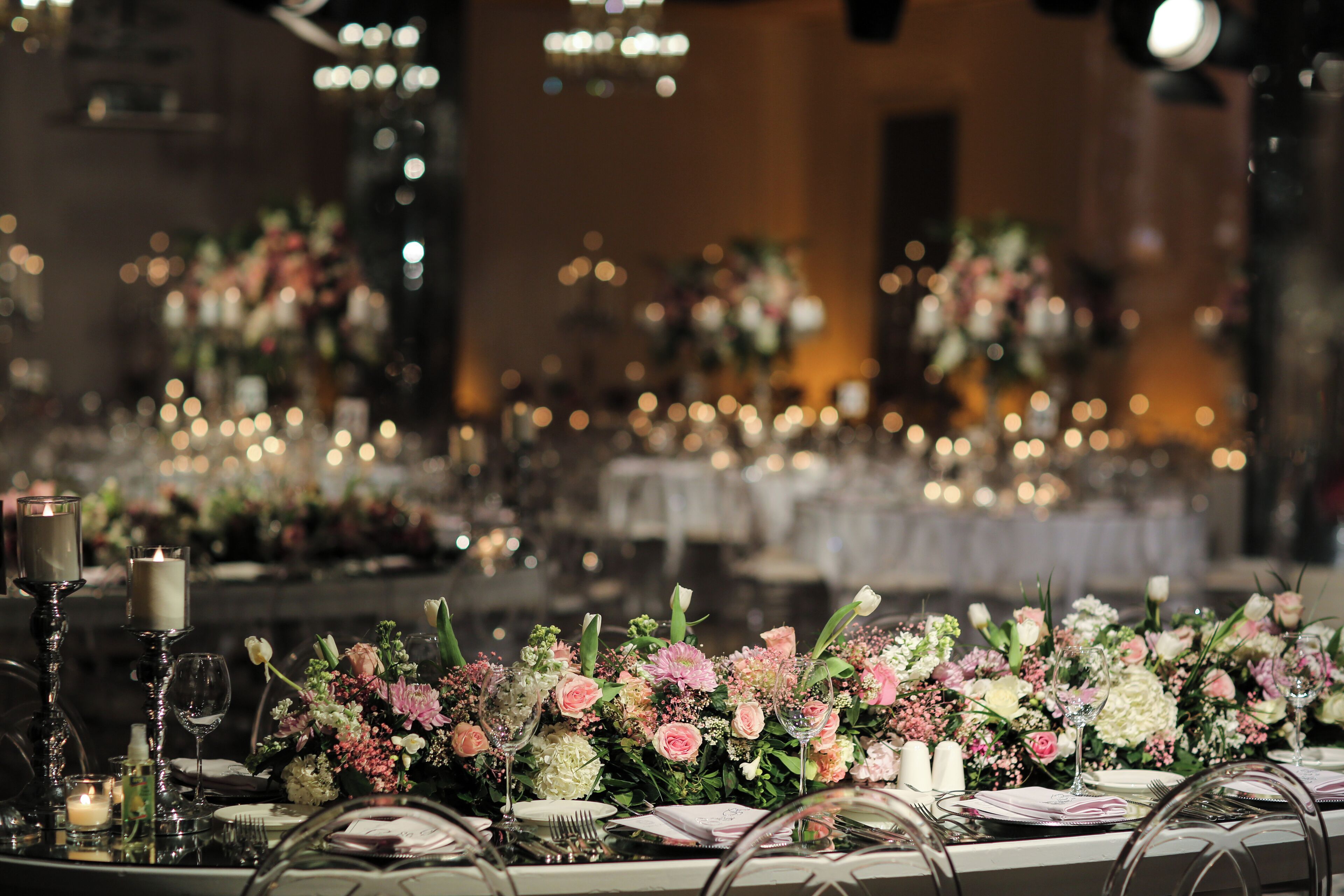 A banquet hall with tables set for a formal event, featuring floral centerpieces and candles.