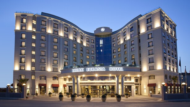 Un hôtel à plusieurs étages, doté d’une entrée imposante, de grandes fenêtres et d’une façade centrale en verre.