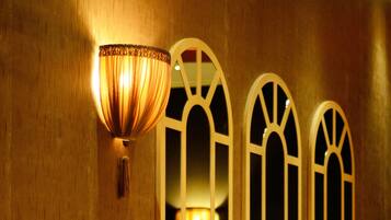 Un pasillo con pared de madera, una lámpara de pared y tres ventanas arqueadas con luces en su interior.