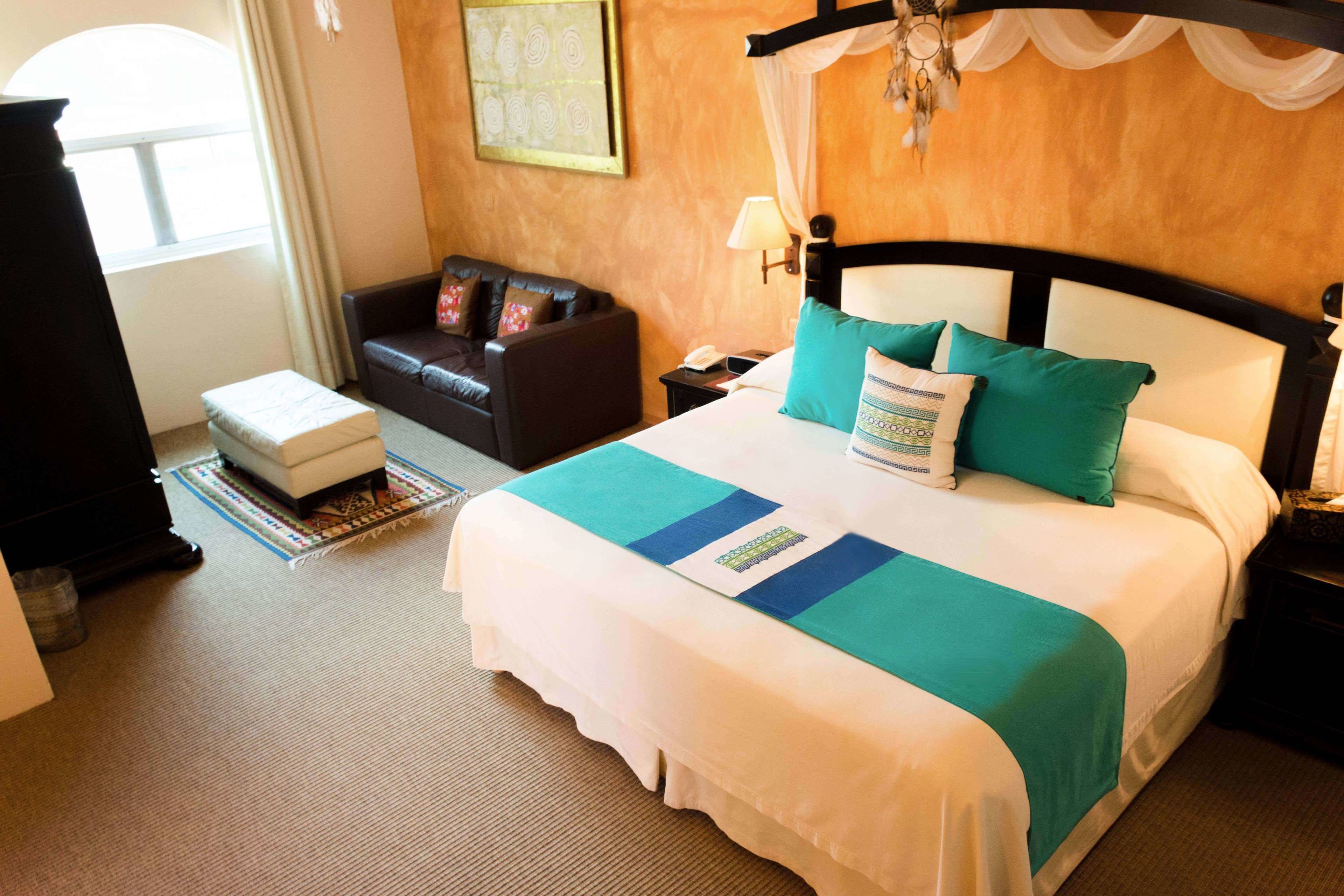 Une chambre d’hôtel avec un grand lit, un canapé, une table de chevet et une fenêtre.