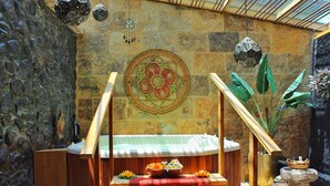 Une pièce avec un mur en pierre, un banc en bois, une table recouverte d’une nappe rouge et une décoration murale.