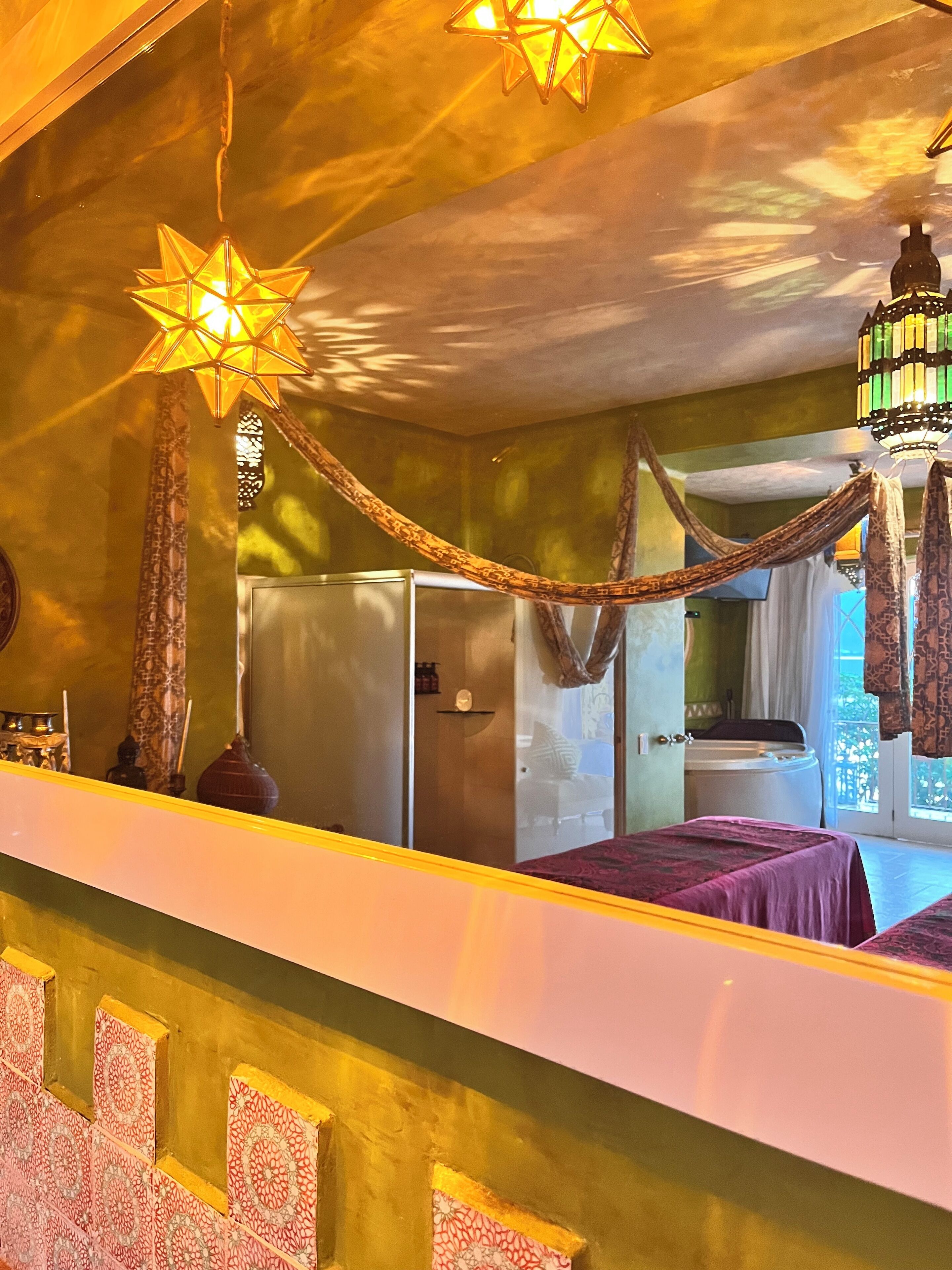 A room with a bed, a mirror, a star-shaped hanging light, and a hammock.