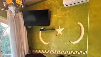 Un baño con una bañera grande, un televisor montado en la pared y una decoración con forma de luna creciente.
