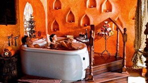 A spa room with a large bathtub, wooden furniture, and decorative arches on the walls. - El Chante Spa Hotel (Jocotepec)