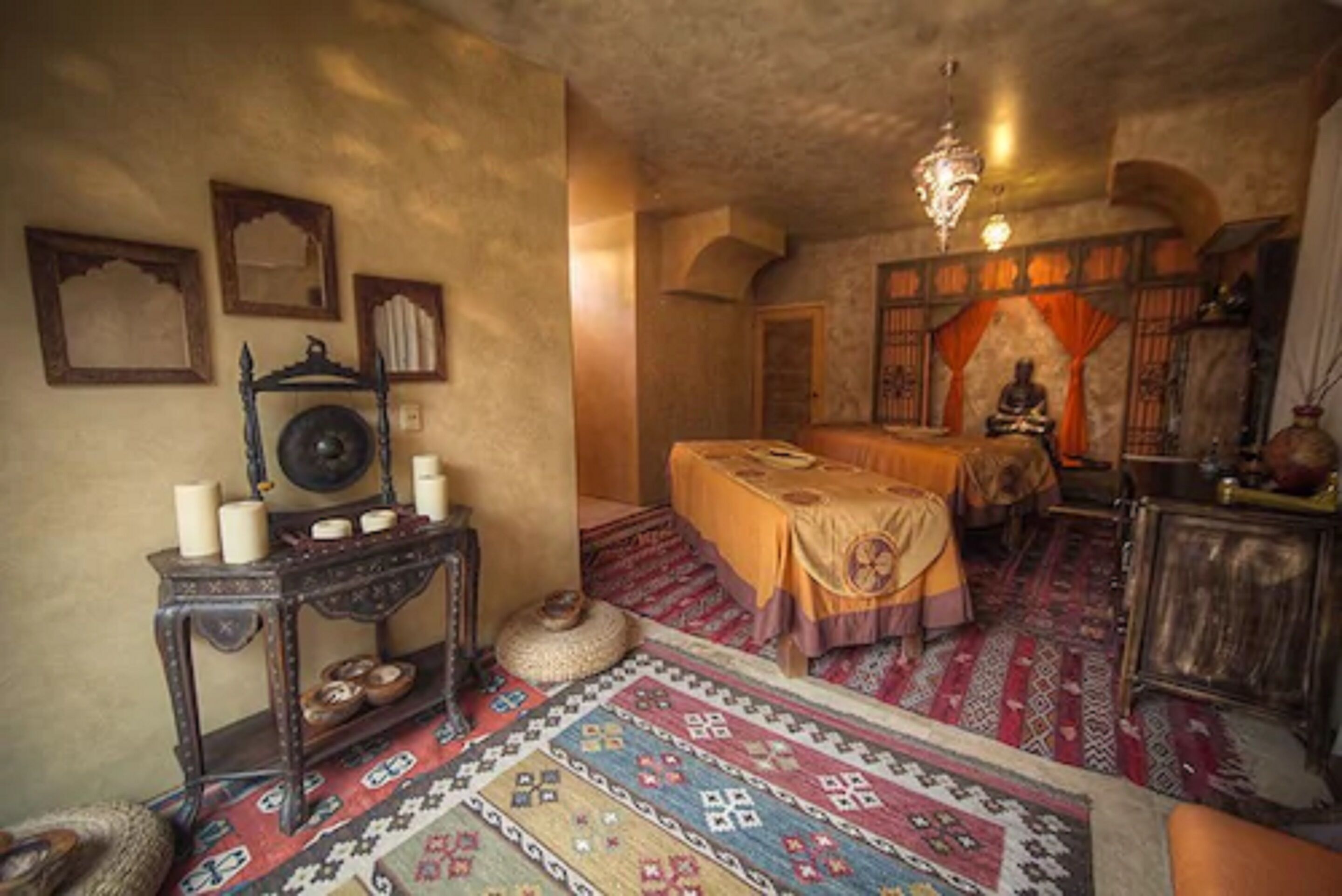 Una habitación tradicional con una cama, una mesita con velas y una alfombra decorativa.
