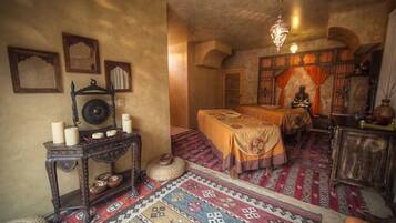 Una habitación tradicional con una cama, una mesita con velas y una alfombra decorativa.