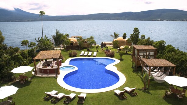 Une piscine avec des chaises longues, un espace barbecue et une vue sur le lac.