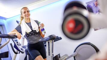 Une personne utilise un tapis de course dans une salle de sport, où l'on peut voir des poids et une bouteille d'eau.