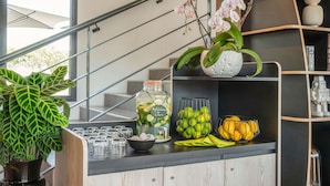 A kitchen counter with a potted plant, a jar of pickles, a bowl of bananas, and a shelf with decorative items. - ibis Styles Pertuis Luberon (Pertuis)