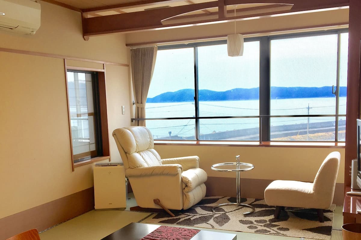 Una habitación con una mesa de comedor, dos sillas, un sofá, una mesita redonda y vistas al mar.