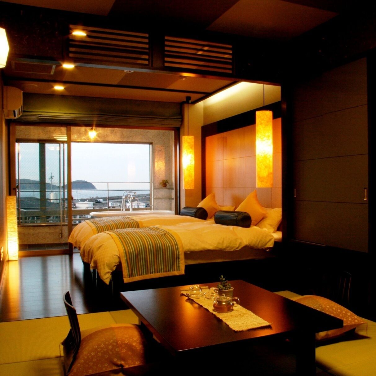 A hotel room with a large bed, a small table, and a view of the city.