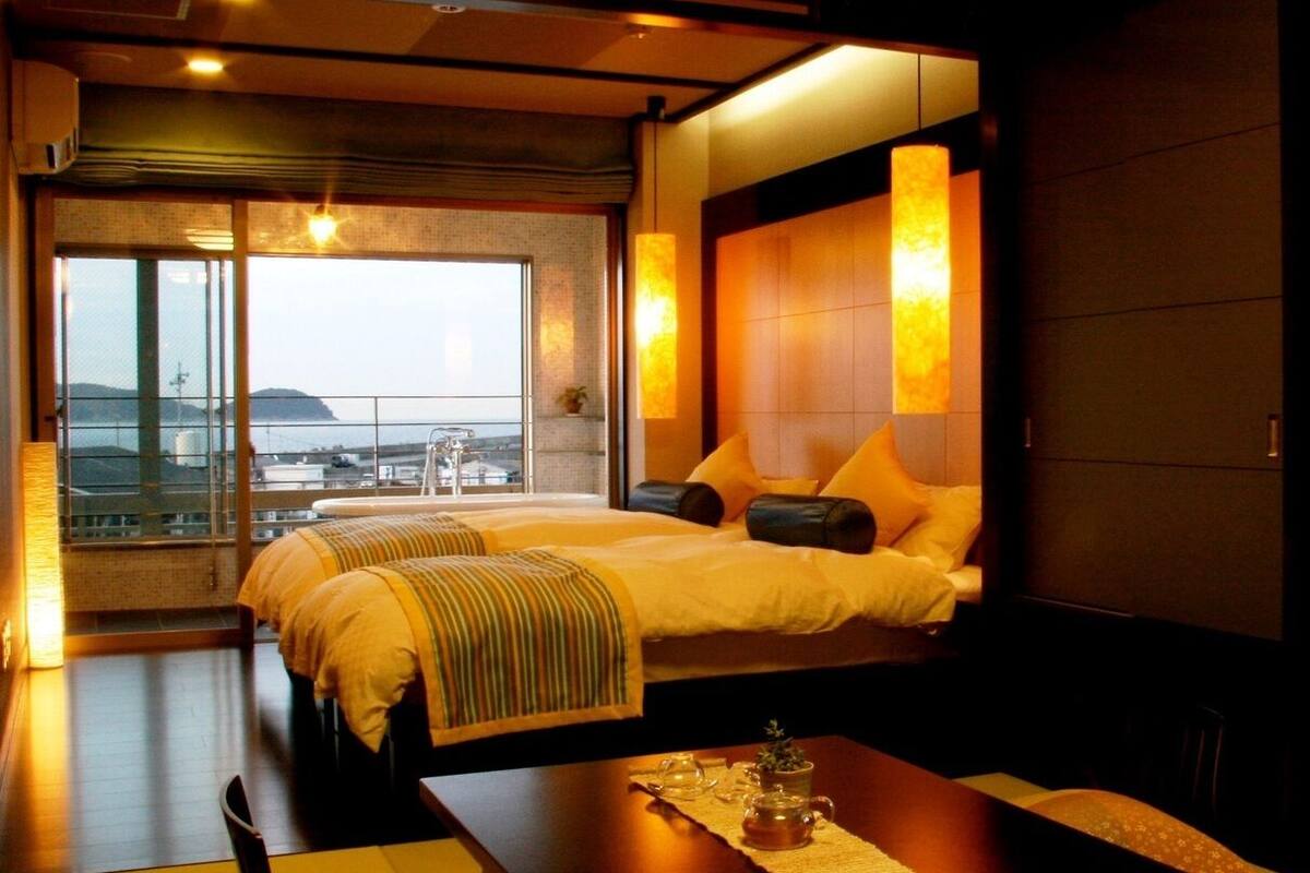 Ein Hotelzimmer mit einem großen Bett, einem kleinen Tisch und Blick auf die Stadt.