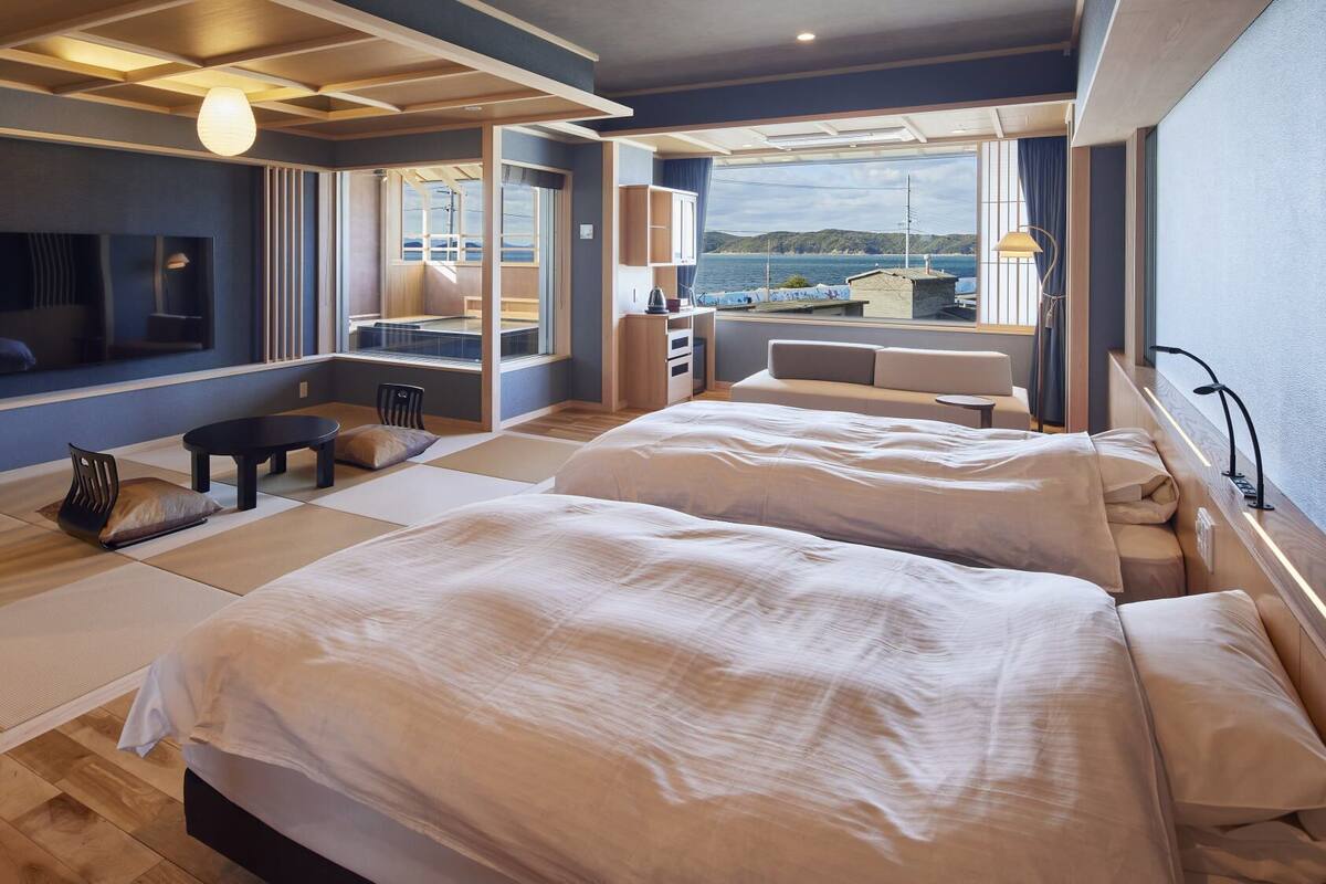 Ein modernes Hotelzimmer mit zwei Betten, einem Fernseher, einem Schreibtisch und Meerblick.