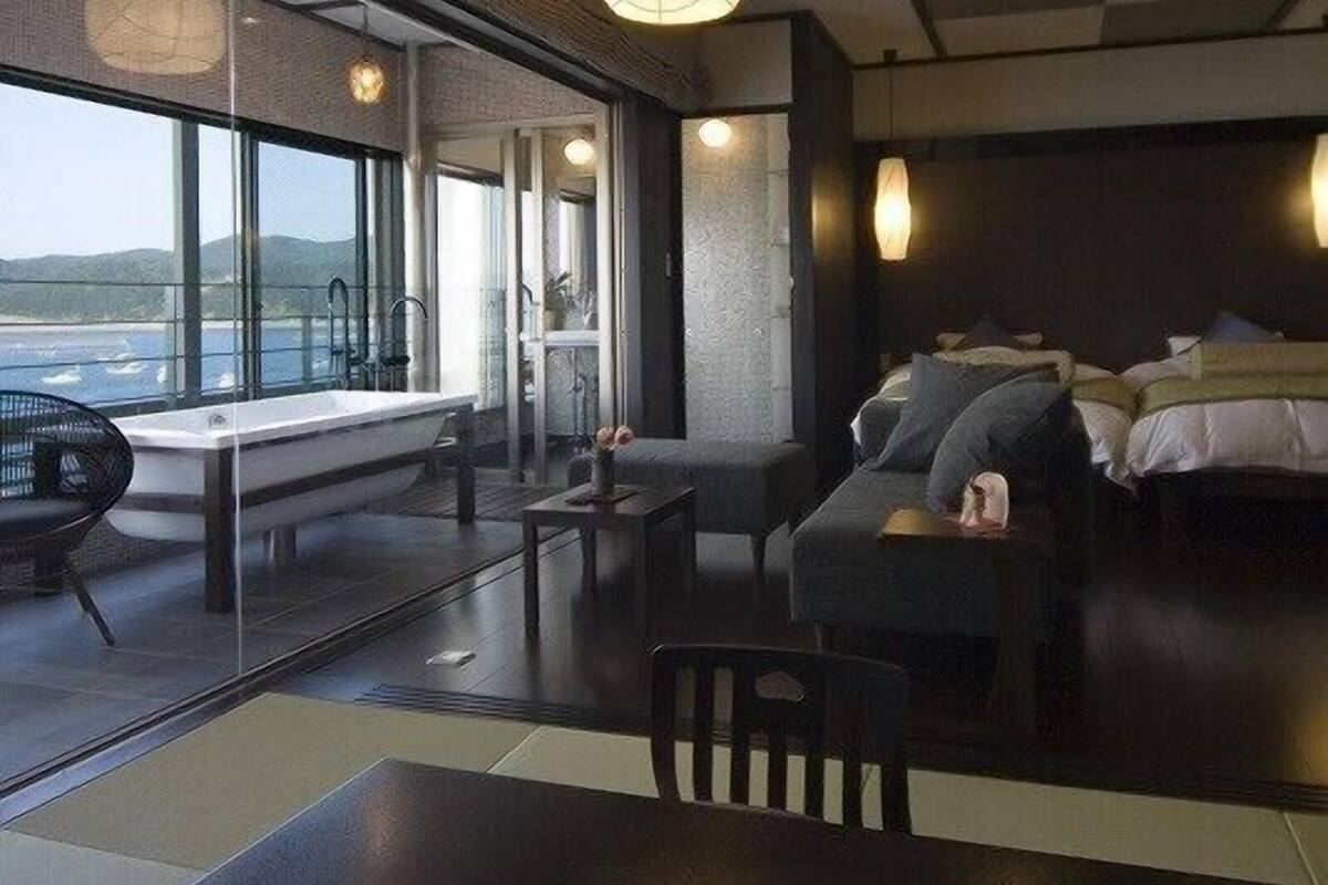 Ein modernes Hotelzimmer mit großem Fenster, einer Couch, einem Tisch und einem Bett.
