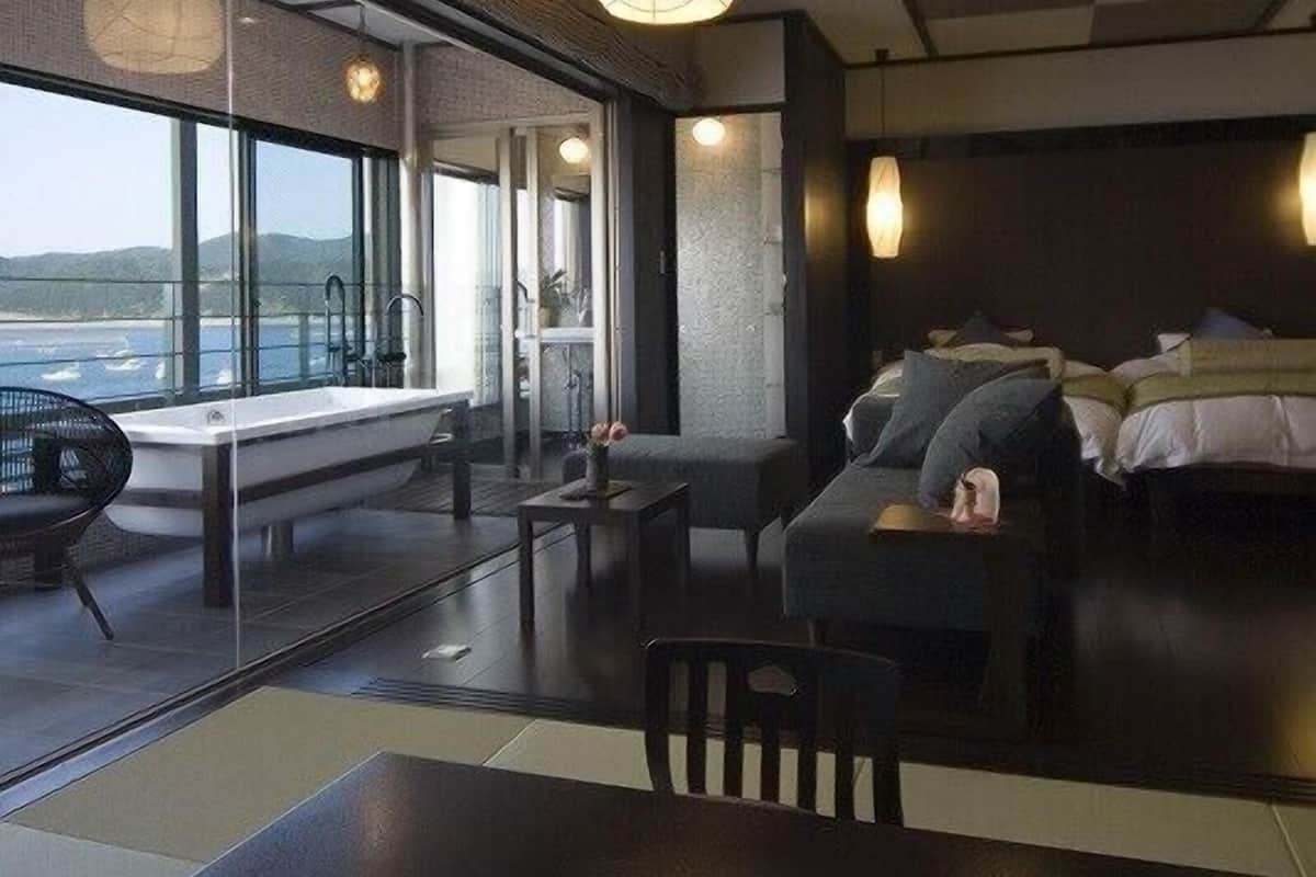 Una habitación de hotel moderna con un ventanal grande, un sofá, una mesa y una cama.