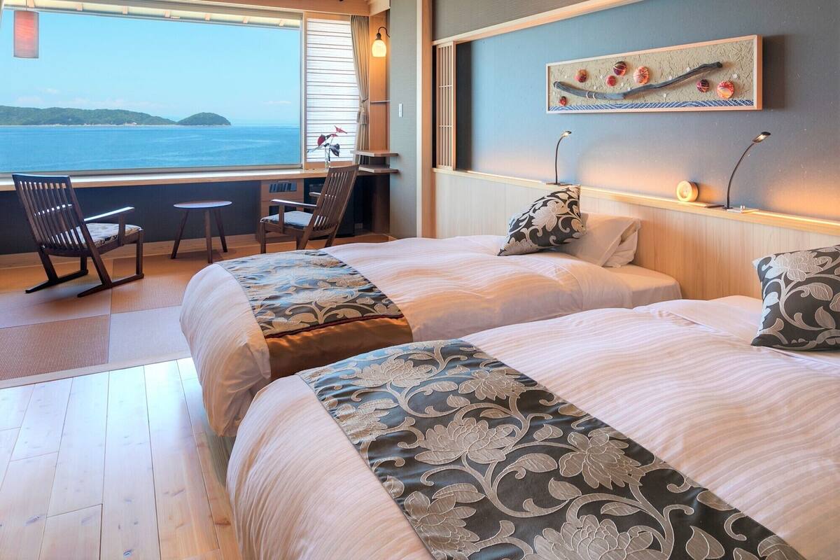 Ein Schlafzimmer mit zwei Betten, einem Schreibtisch und Meerblick.