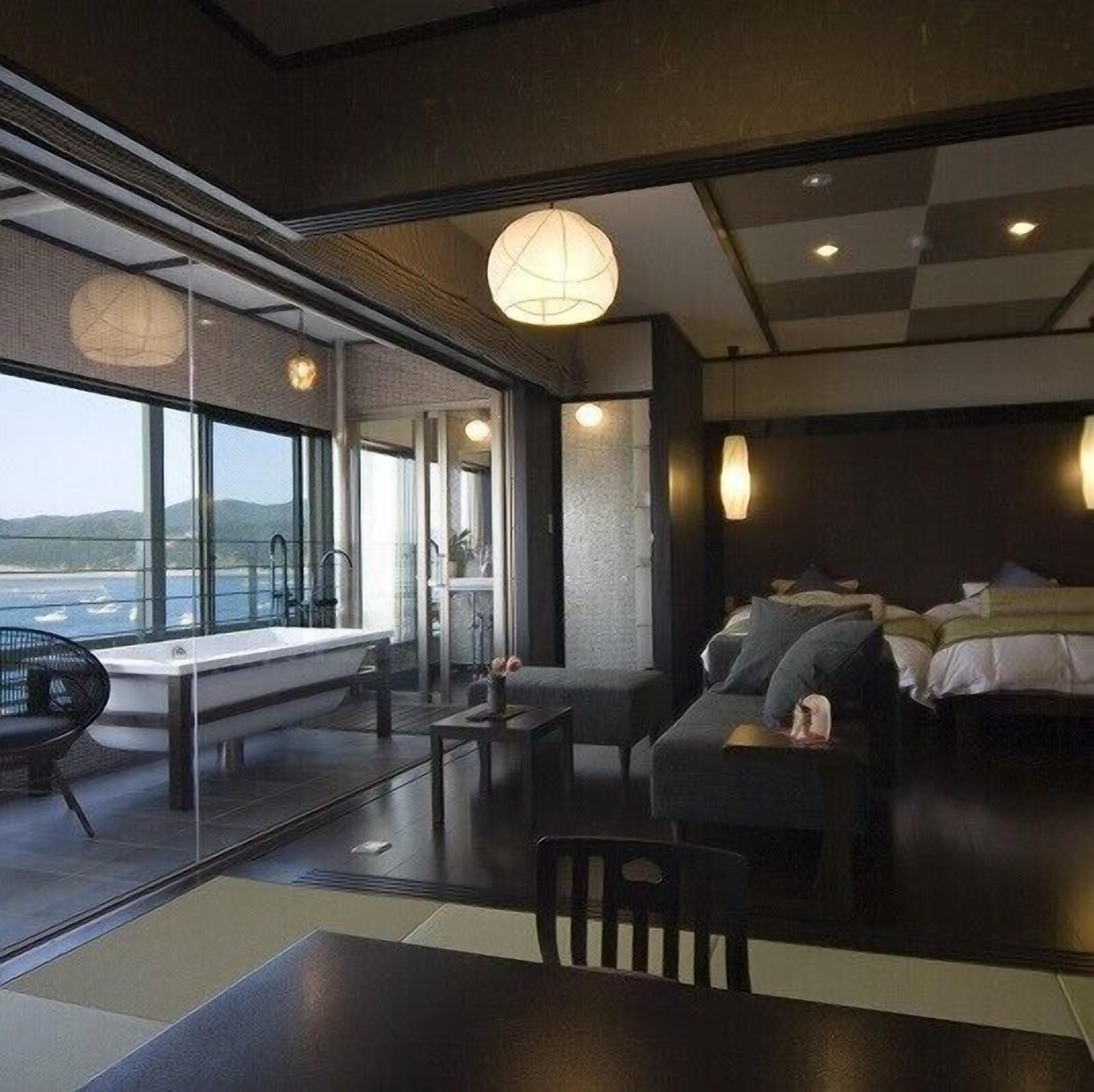 Una habitación de hotel moderna con un ventanal grande, un sofá, una mesa y una cama.