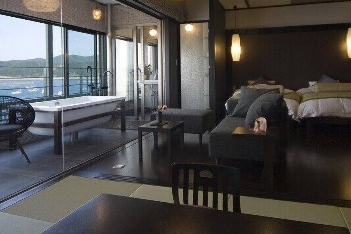 Ein modernes Hotelzimmer mit großem Fenster, einer Couch, einem Tisch und einem Bett.