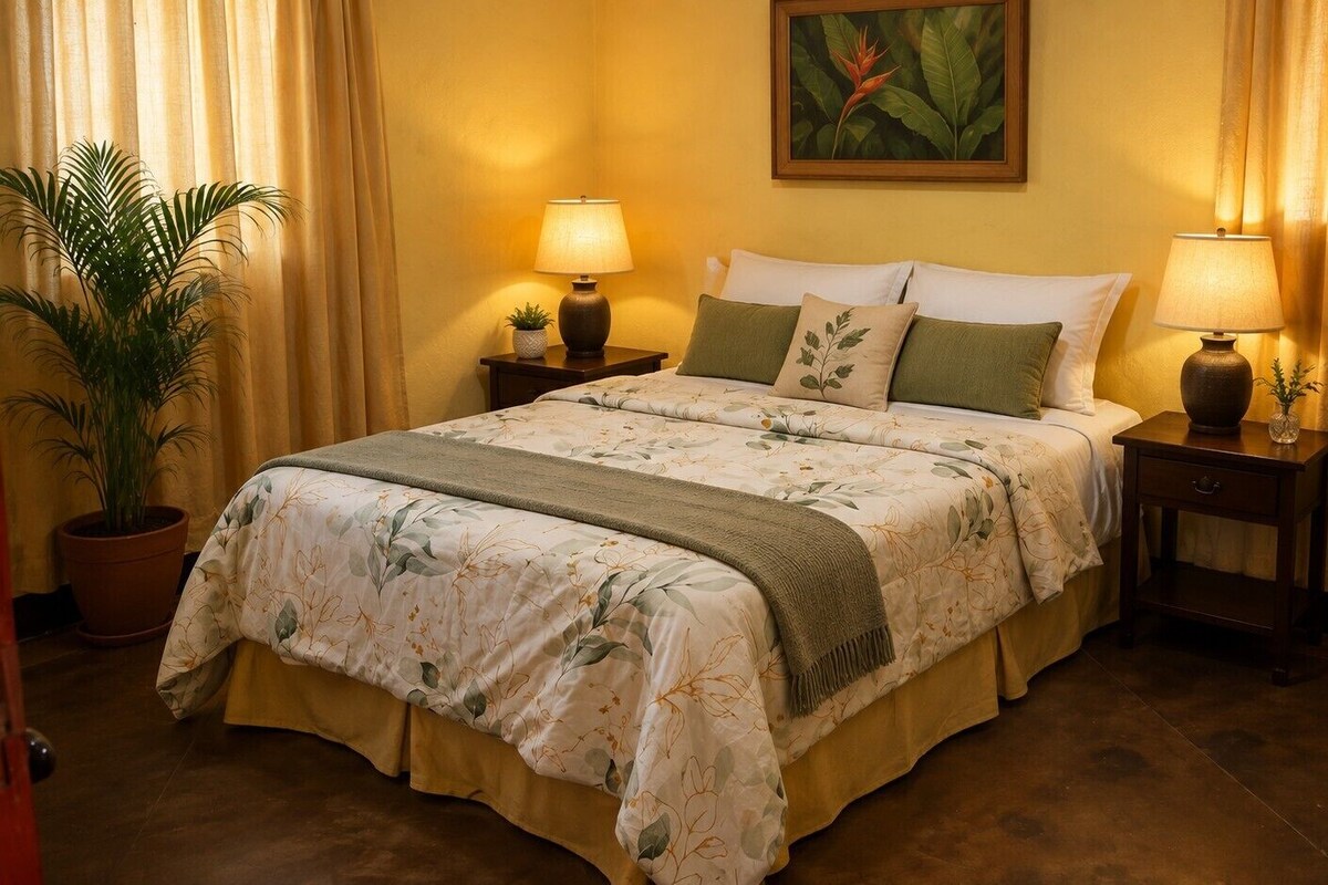 A hotel room with a bed, two bedside tables, a potted plant, and a painting on the wall.