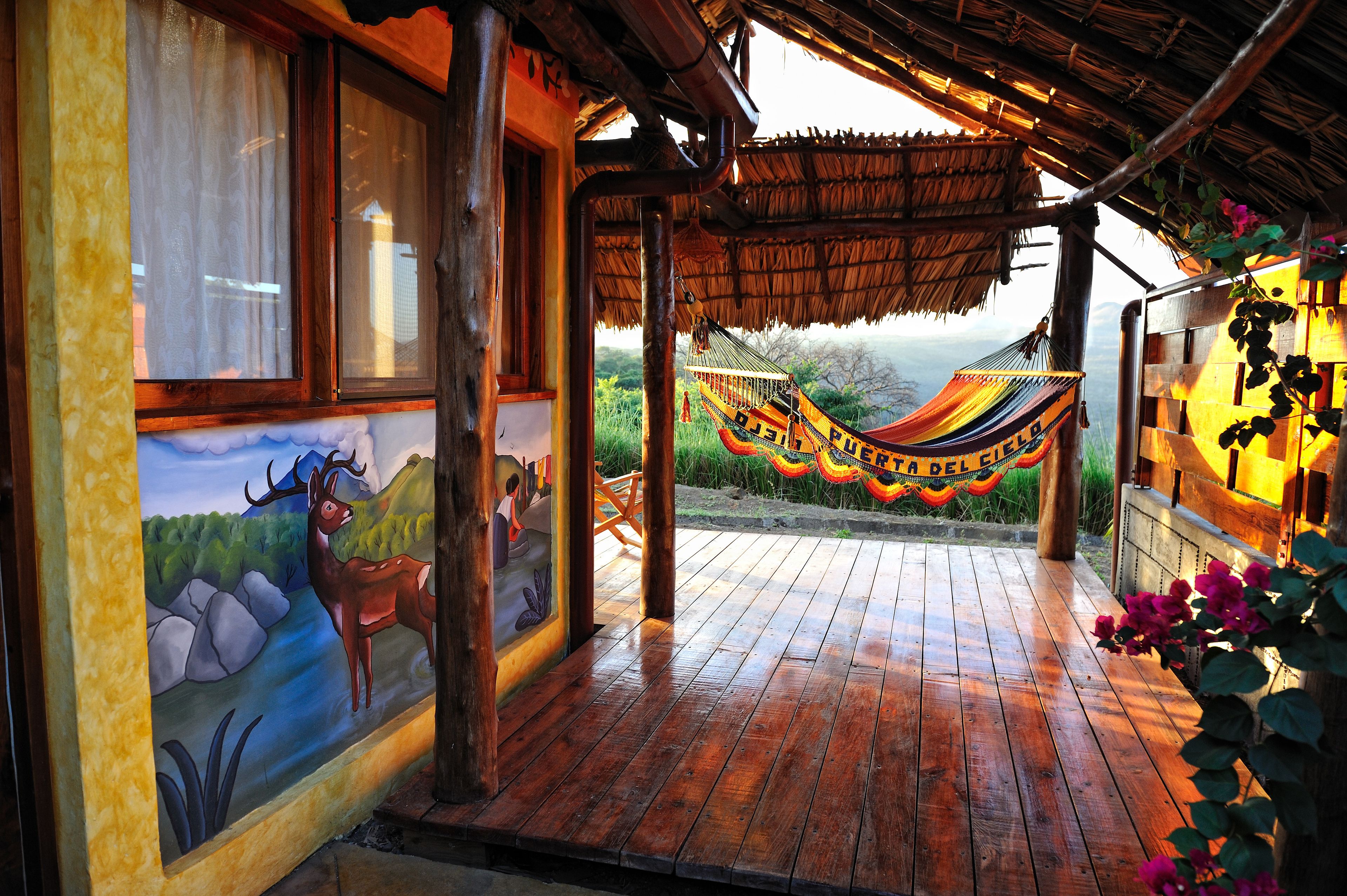 A wooden porch with a hammock, a mural of a deer, and a view of the mountains.