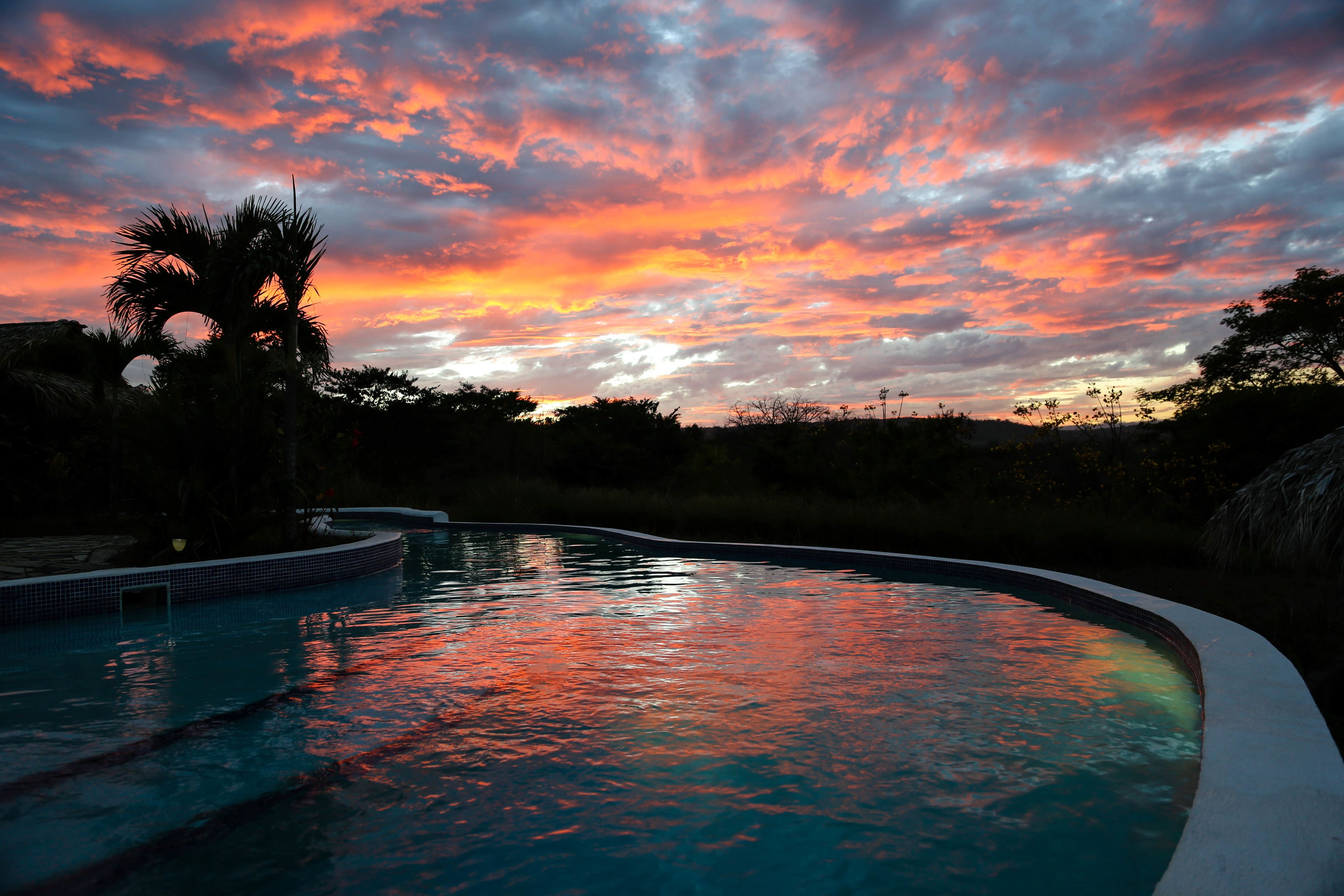 A swimming pool at sunset with a sunset sky reflected on the water.