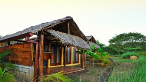 A rustic wooden house with a thatched roof, surrounded by lush greenery. - Hacienda Puerta Del Cielo Ecolodge & Spa (Nandasmo)