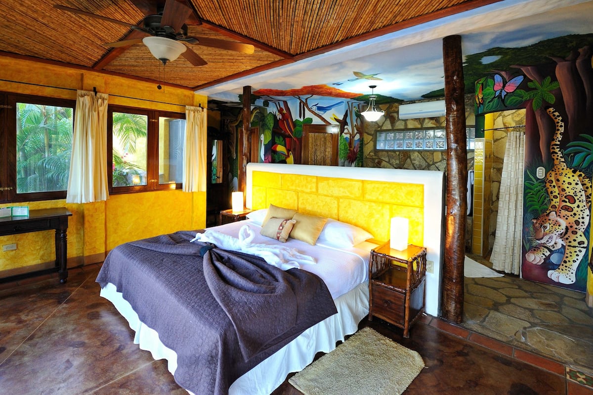 A room with a large bed, wooden headboard, and a mural of jungle animals.