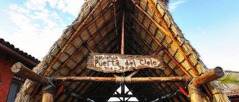Una estructura con techo de paja y un letrero que dice "Puerta del Cielo".