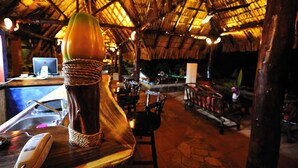 A rustic interior with a thatched roof, wooden furniture, and a bar area with a bottle and glasses. - Hacienda Puerta Del Cielo Ecolodge & Spa (Nandasmo)