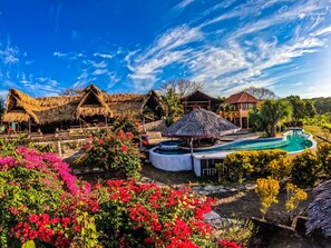 A resort with thatched-roof huts, a swimming pool, and lush gardens. - Hacienda Puerta Del Cielo Ecolodge & Spa (Nandasmo)