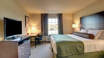 A hotel room with a bed, a desk, a chair, a television, and a dresser.