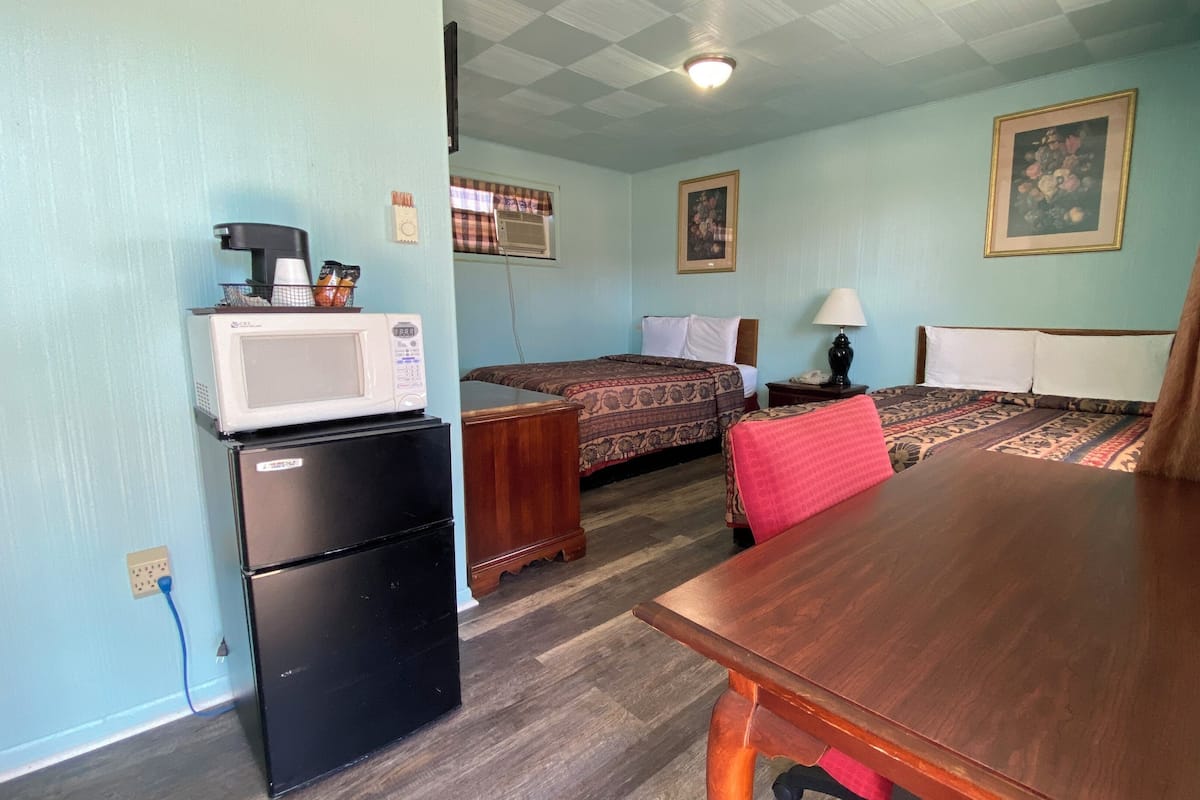 A small, compact room with a bed, a desk, a microwave, and a refrigerator.