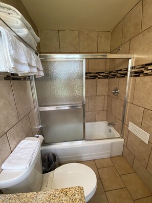 Une salle de bain dotée d’une douche à parois de verre, d’une baignoire, de toilettes et d’un comptoir en granit.