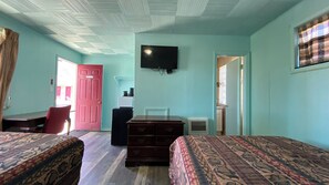 Une chambre avec deux lits, un bureau, une chaise, une télévision et une porte.