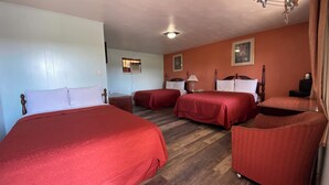 Ein Hotelzimmer mit zwei Betten, Holzboden, einer Deckenleuchte und einem gerahmten Bild an der Wand.