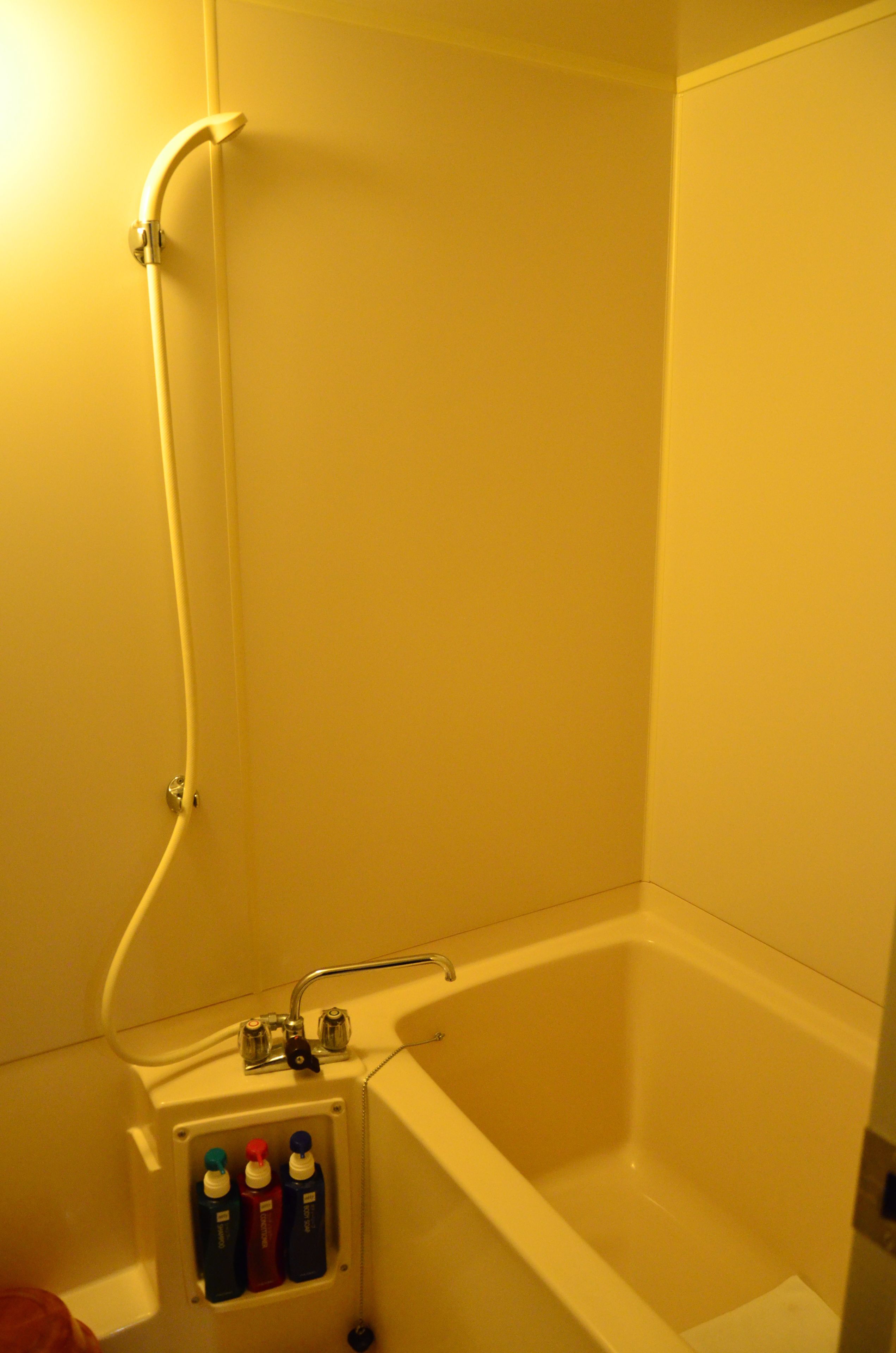 Un baño con bañera, ducha y un mueble de pared para medicinas con botellas.