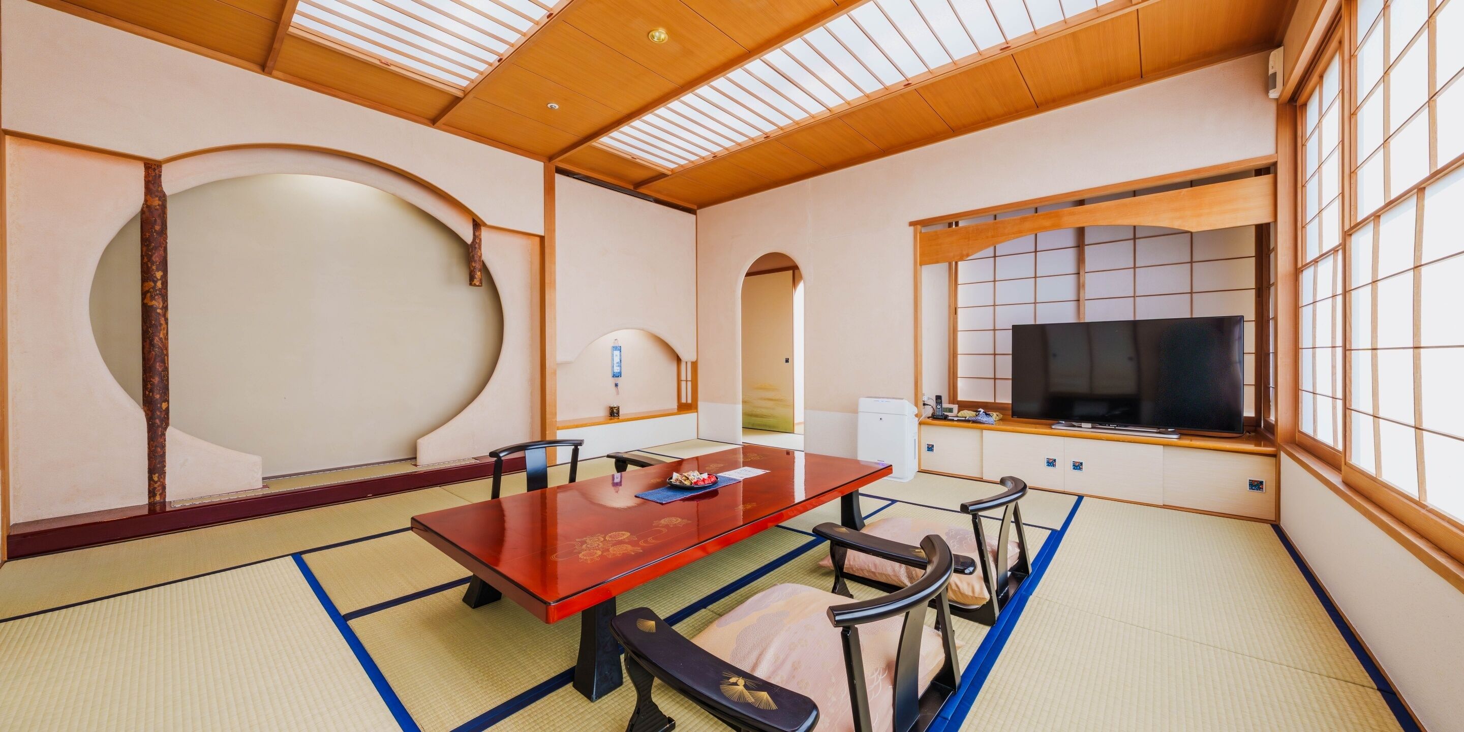 Une pièce de style japonais traditionnel, avec un sol recouvert de tatamis, une table basse et un téléviseur.
