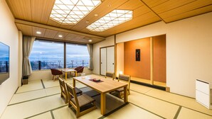 A traditional Japanese-style room with tatami flooring, a wooden table, chairs, a television, and a large window offering a view. - Onyado Toho（ORIX HOTELS & RESORTS） (Aizuwakamatsu)