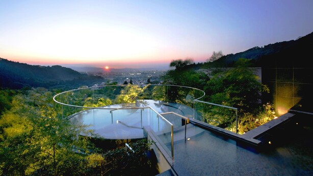 A modern infinity pool with a glass railing, surrounded by lush greenery and overlooking a valley. - Onyado Toho（ORIX HOTELS & RESORTS） (Aizuwakamatsu)