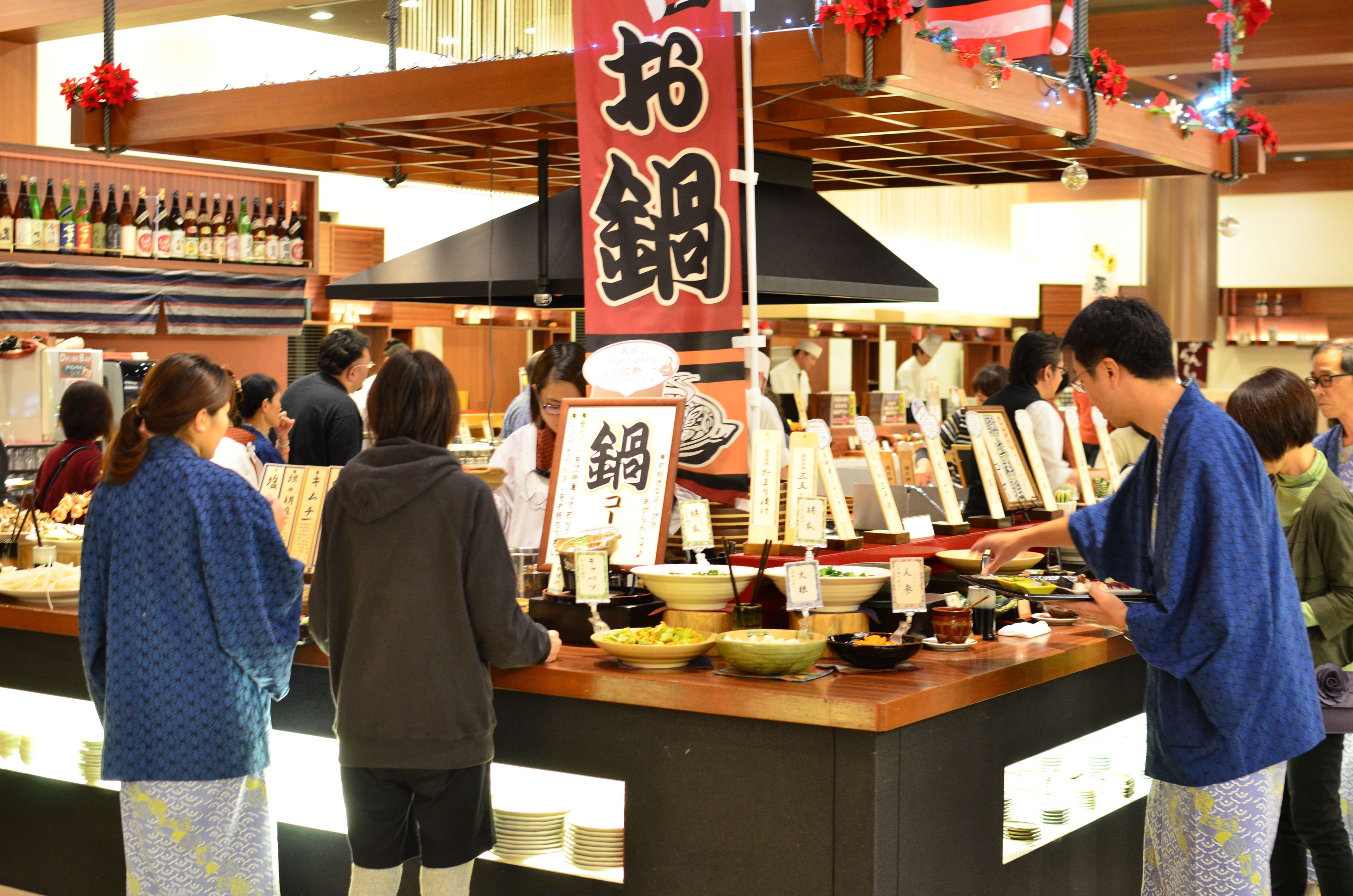 A sushi bar with a variety of dishes and a large red banner with Japanese characters.