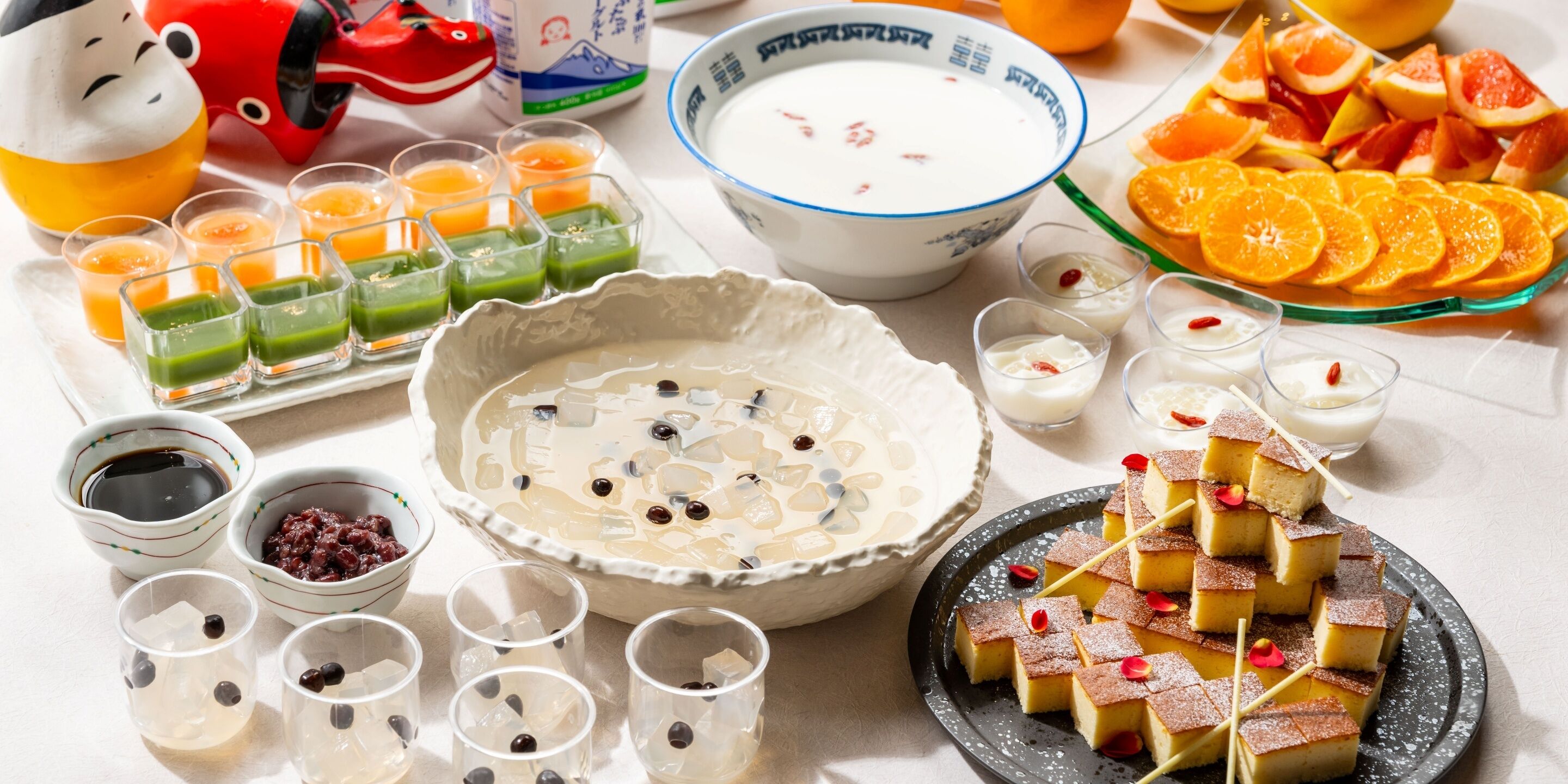 Una mesa con diversos alimentos, entre ellos, un tazón de sopa, un plato de fruta y varios vasos de bebidas.
