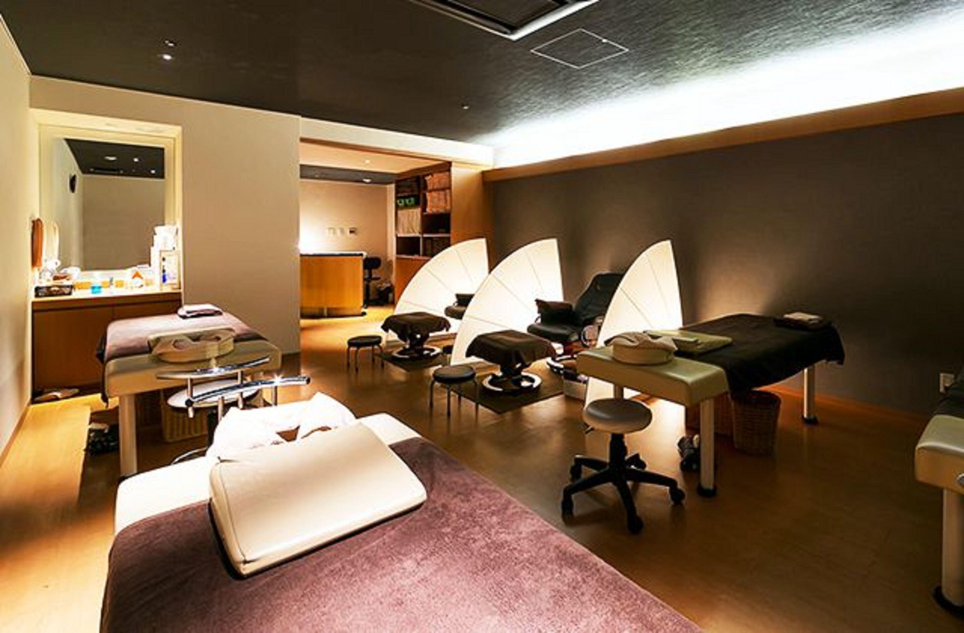 A room with a bed, a desk, a chair, and a massage table.