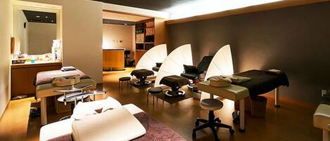 A room with a bed, a desk, a chair, and a massage table.