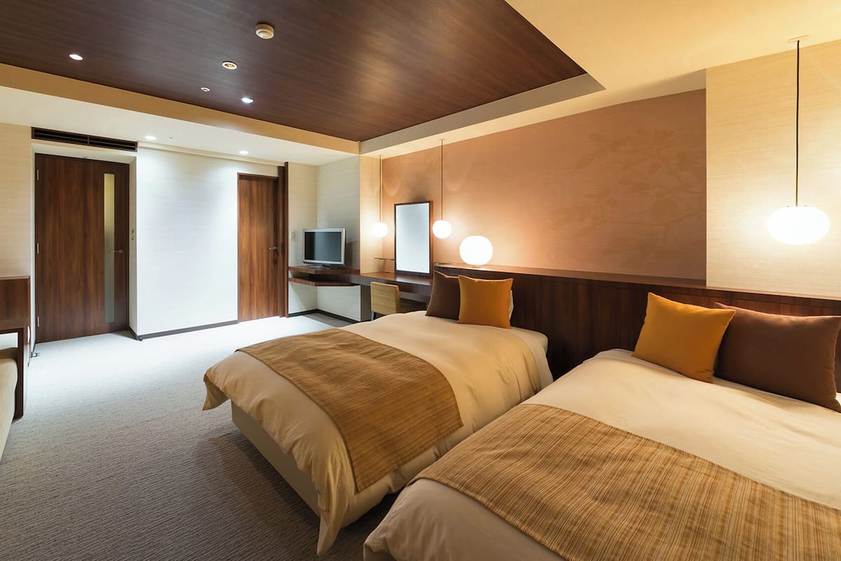 Una habitación de hotel con una cama grande, un escritorio, televisor y baño.