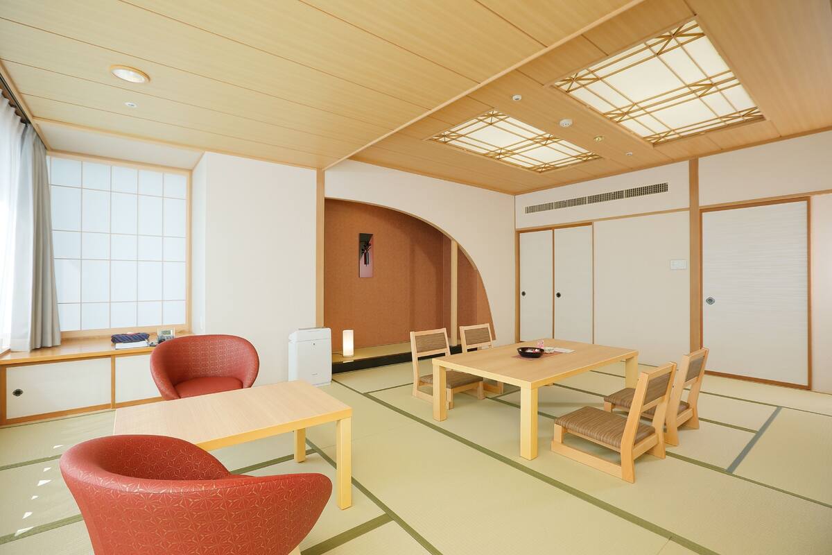 Una habitación japonesa tradicional con suelo de tatami, una mesa baja y sillas de madera.