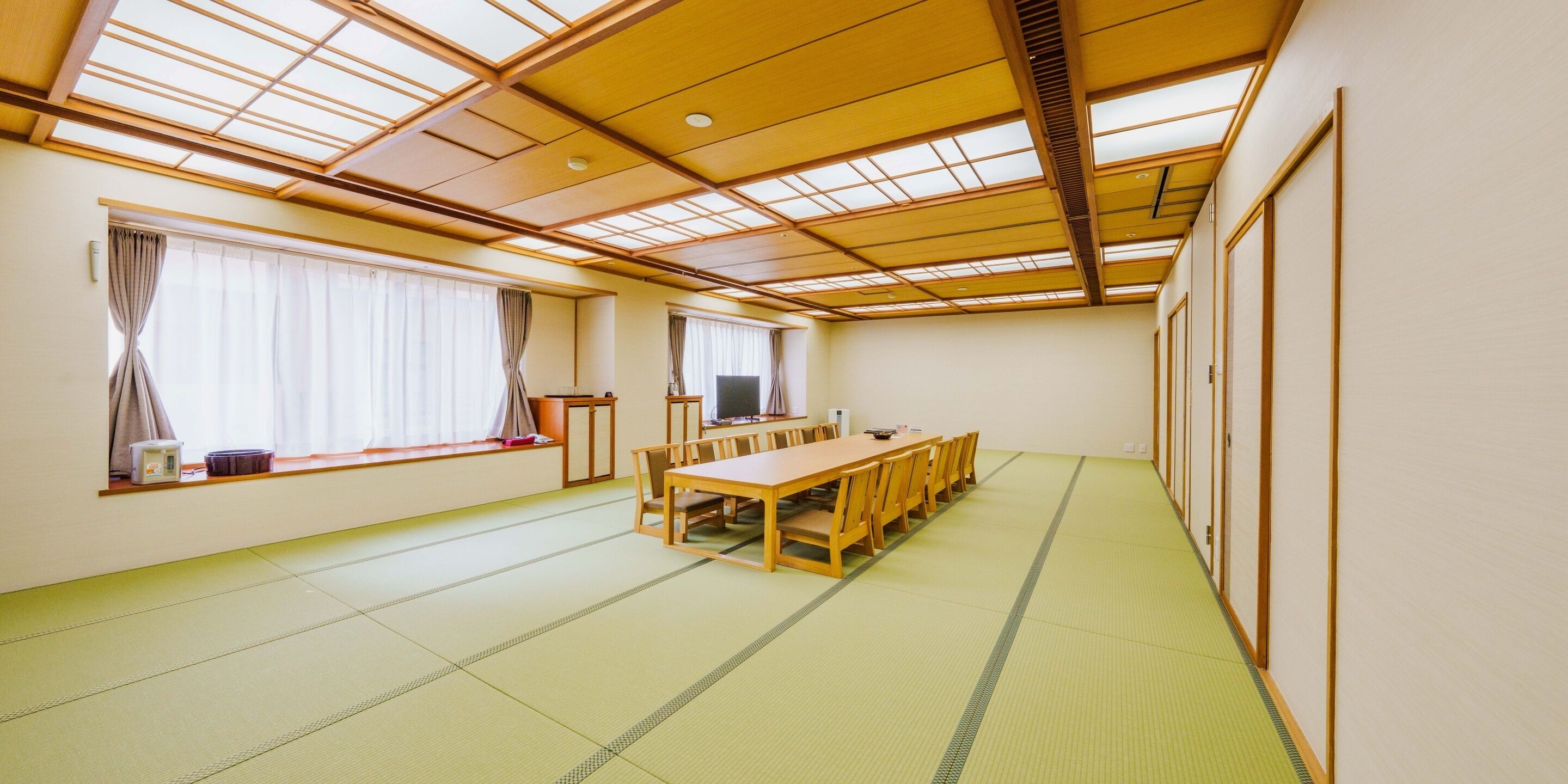 A room with tatami flooring, a wooden table, and a TV.