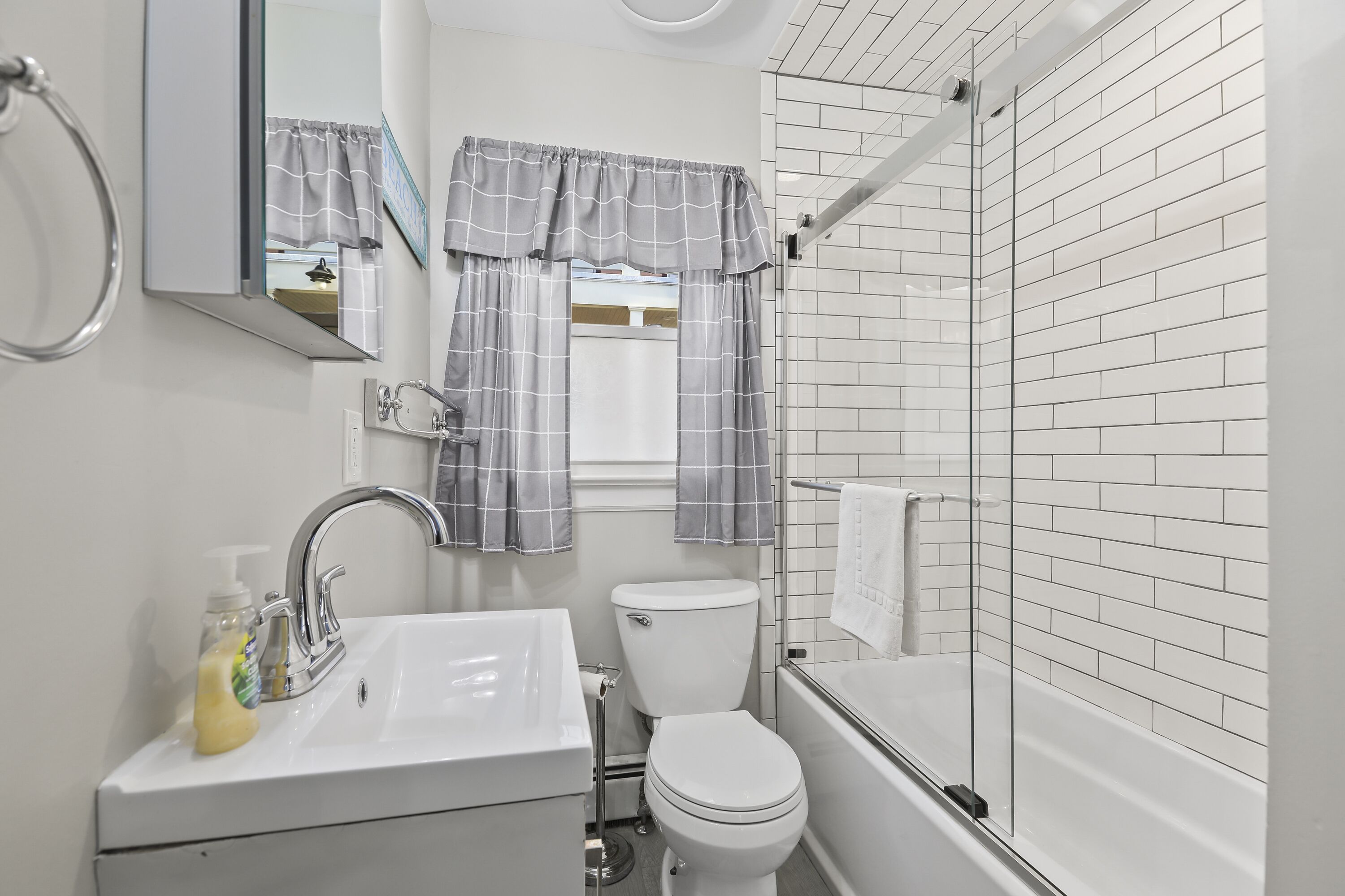 Baño con lavamanos blanco, inodoro y ducha con mampara de vidrio.