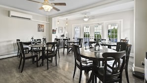 A spacious dining area with wooden tables and chairs, ceiling fans, and large windows providing natural light. - The Inn at Ocean Grove (Ocean Grove)