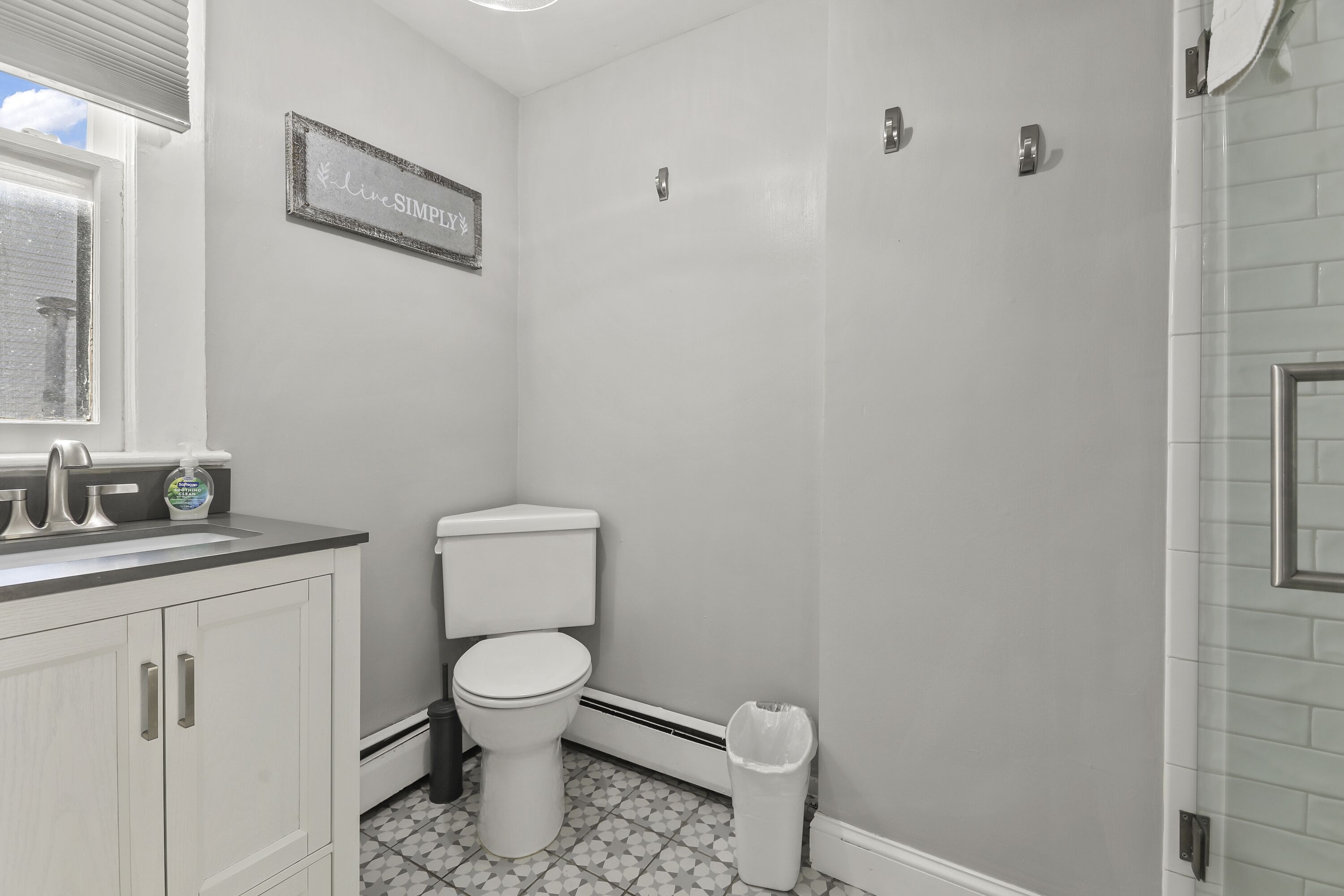 A bathroom with a toilet, a sink, and a trash can.