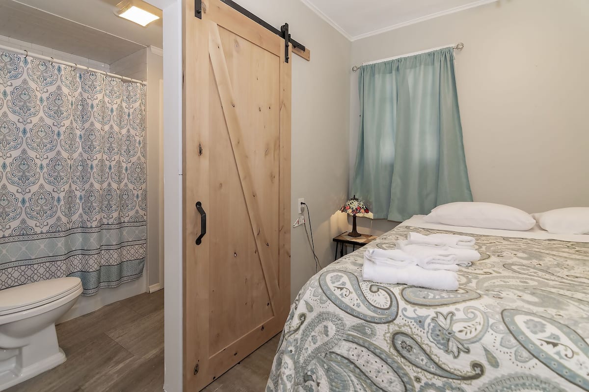 A bathroom with a toilet, a wooden sliding door, and patterned curtains.